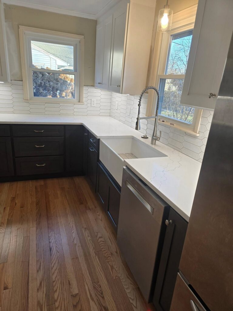 West Hartford CT kitchen remodel after photo with dark lower cabinets, white quartz counters, and picket tile backsplash