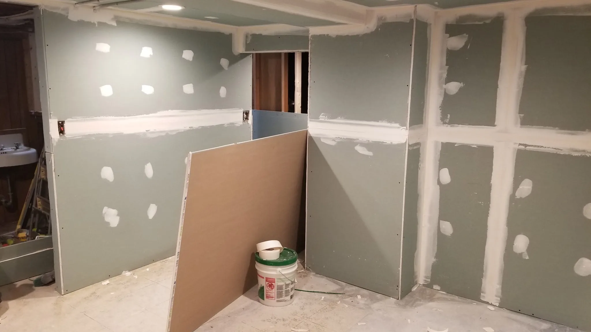Basement renovation in progress with new moisture-resistant drywall hung and seams taped