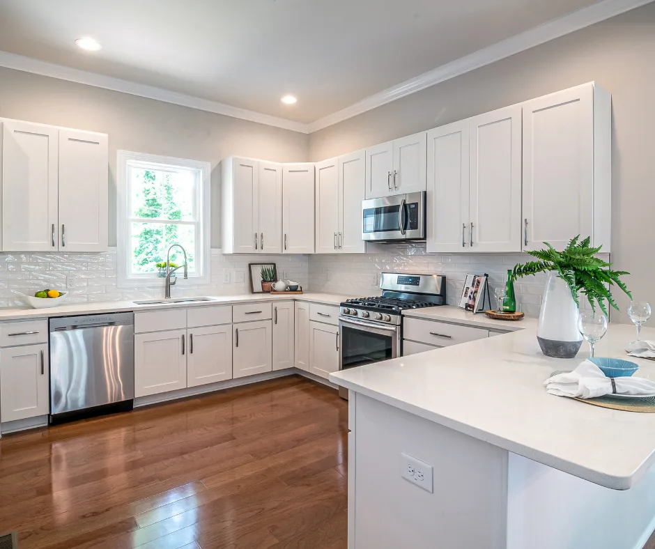 Bright white shaker kitchen with subway tile backsplash, stainless appliances, and wood-look floors