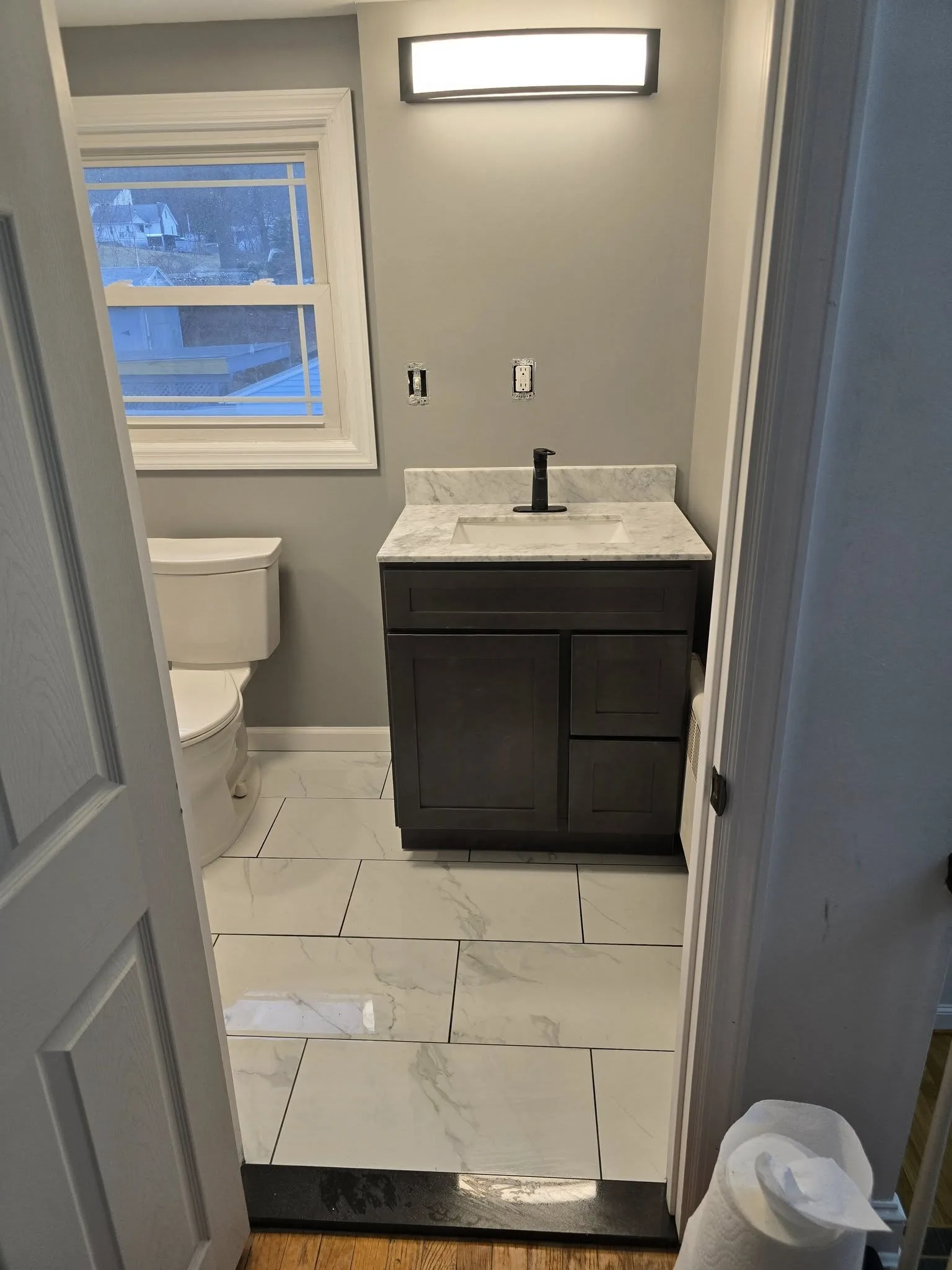 Remodeled Bristol CT bathroom with dark vanity, marble countertop, and marble-look tile floor