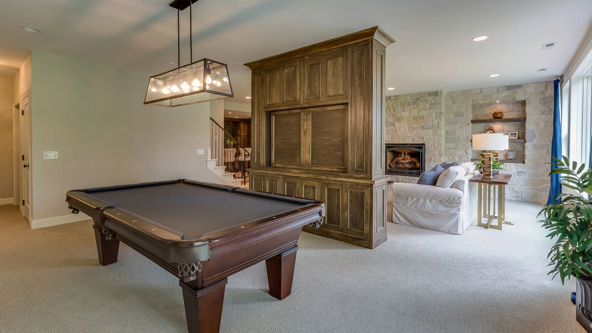 Finished basement with pool table, stone fireplace wall, and custom media cabinet