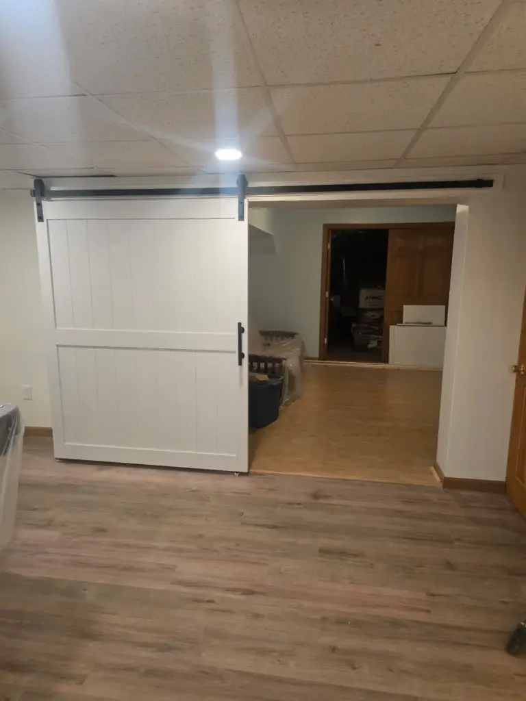 Finished basement remodel with white sliding barn door and vinyl plank flooring