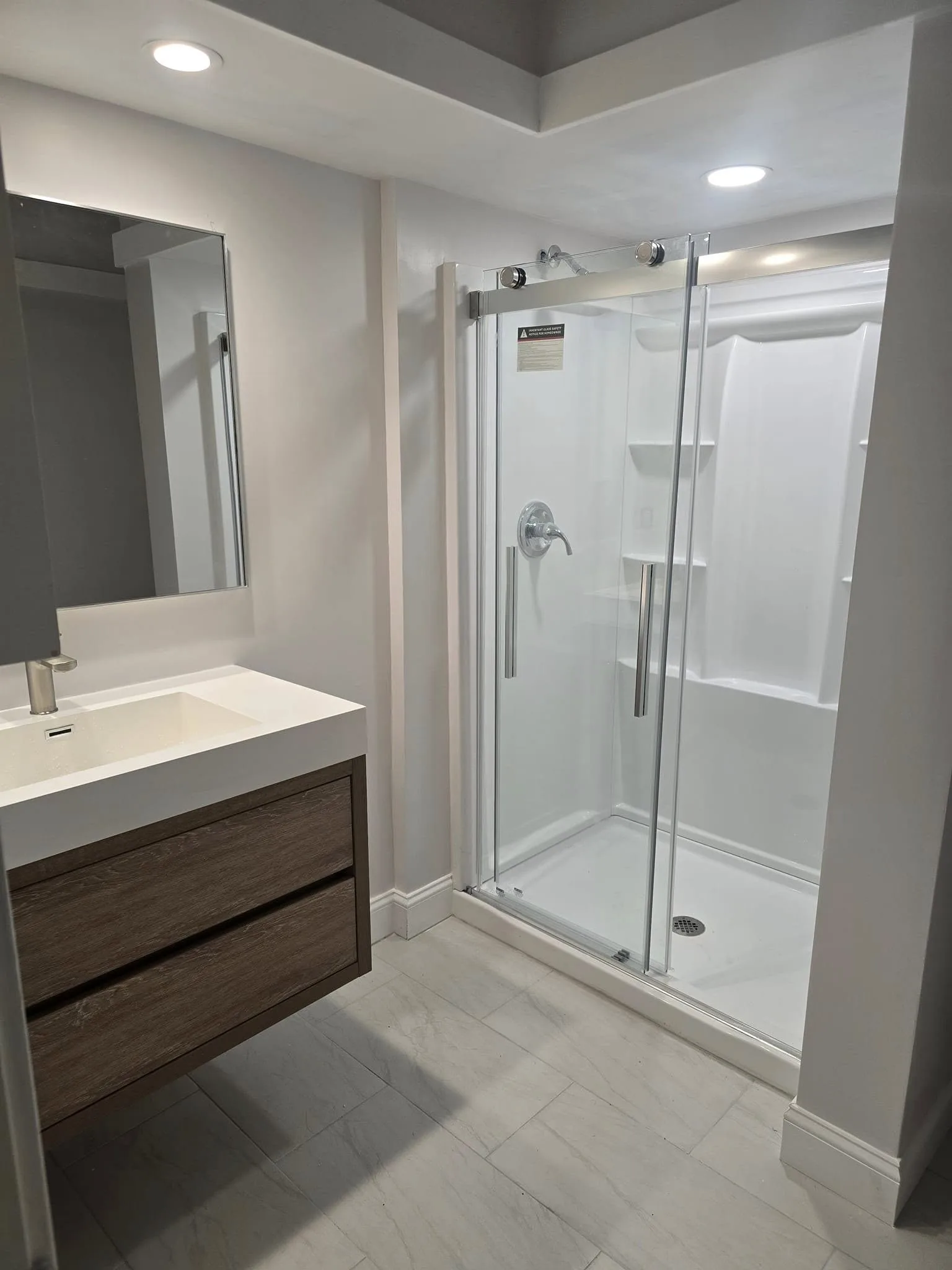 Remodeled Simsbury CT bathroom with floating wood vanity and glass sliding shower