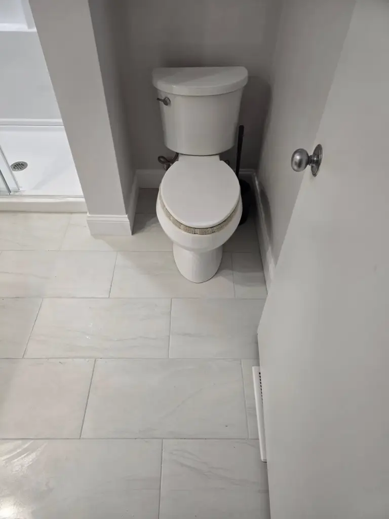 New water-efficient toilet and marble-look tile in a remodeled Simsbury CT bathroom