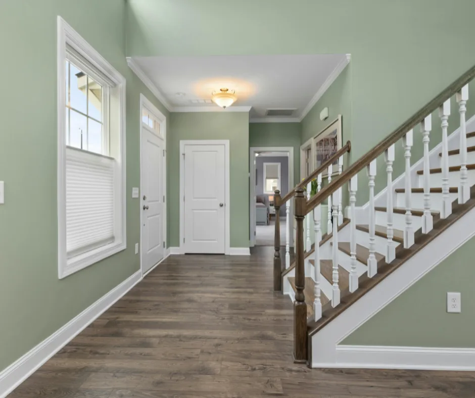 Entryway with new wood-look flooring, sage green paint, and refinished staircase