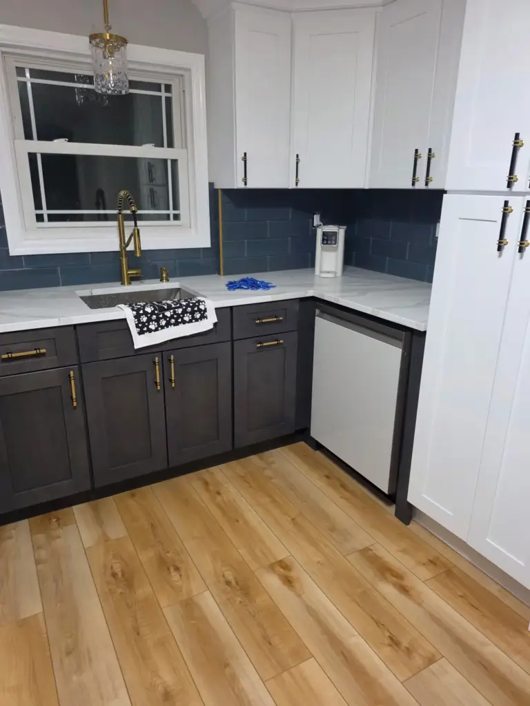 New dishwasher and white pantry cabinets beside charcoal sink cabinets in a Bristol CT kitchen remodel