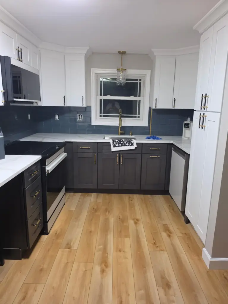 Remodeled Bristol CT kitchen with white shaker uppers, charcoal base cabinets, quartz counters, and brass hardware