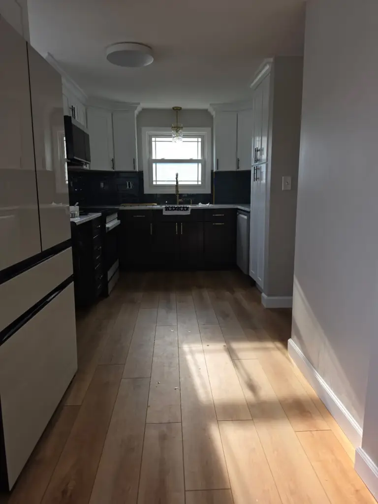 Two-tone Bristol CT kitchen remodel with new wood-look plank flooring and relocated refrigerator