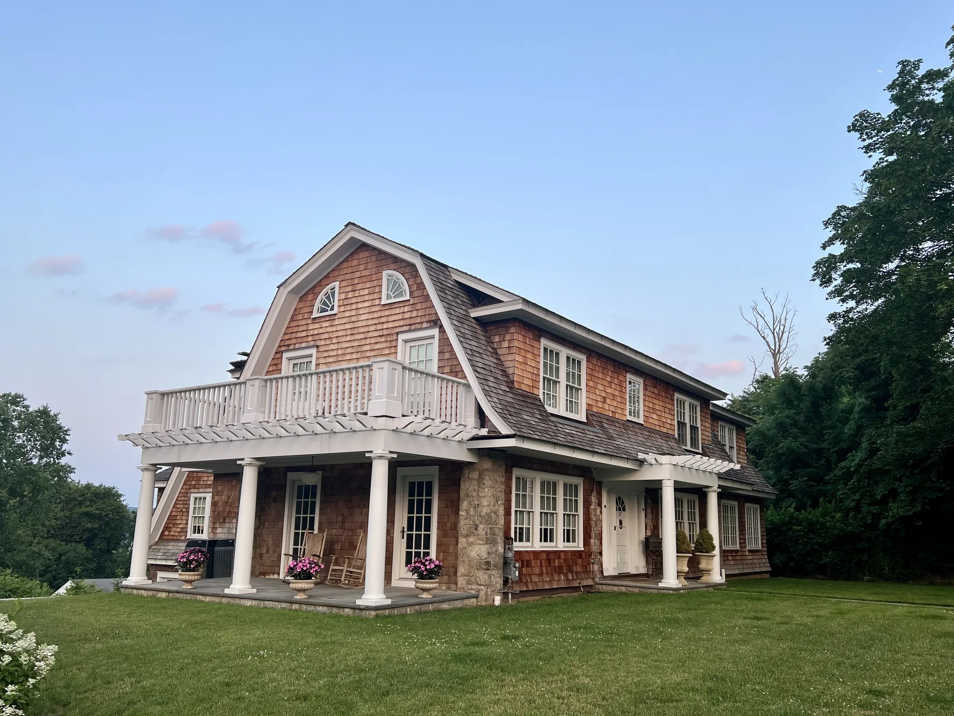 A restored Dutch Colonial house in Connecticut with cedar shingle siding and a covered front porch