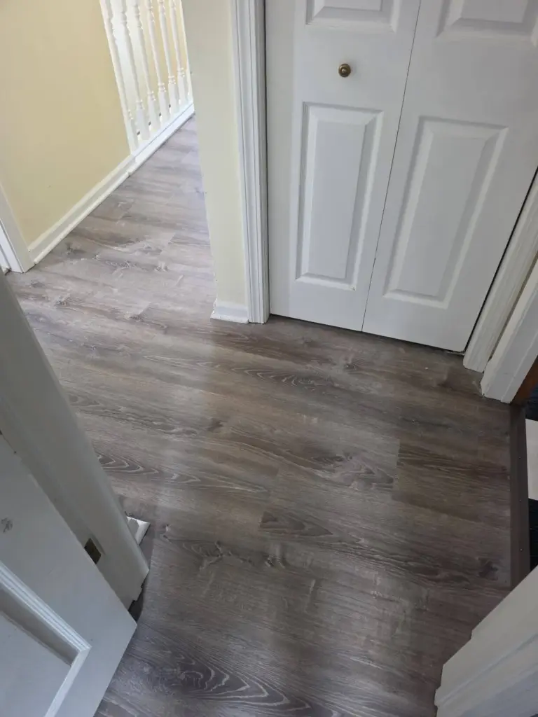 New gray wood-look luxury vinyl plank flooring running through the doorway into the upstairs hallway