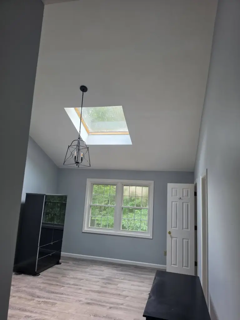 Finished vaulted room with a smooth painted ceiling after popcorn texture removal, new flooring, and fresh paint