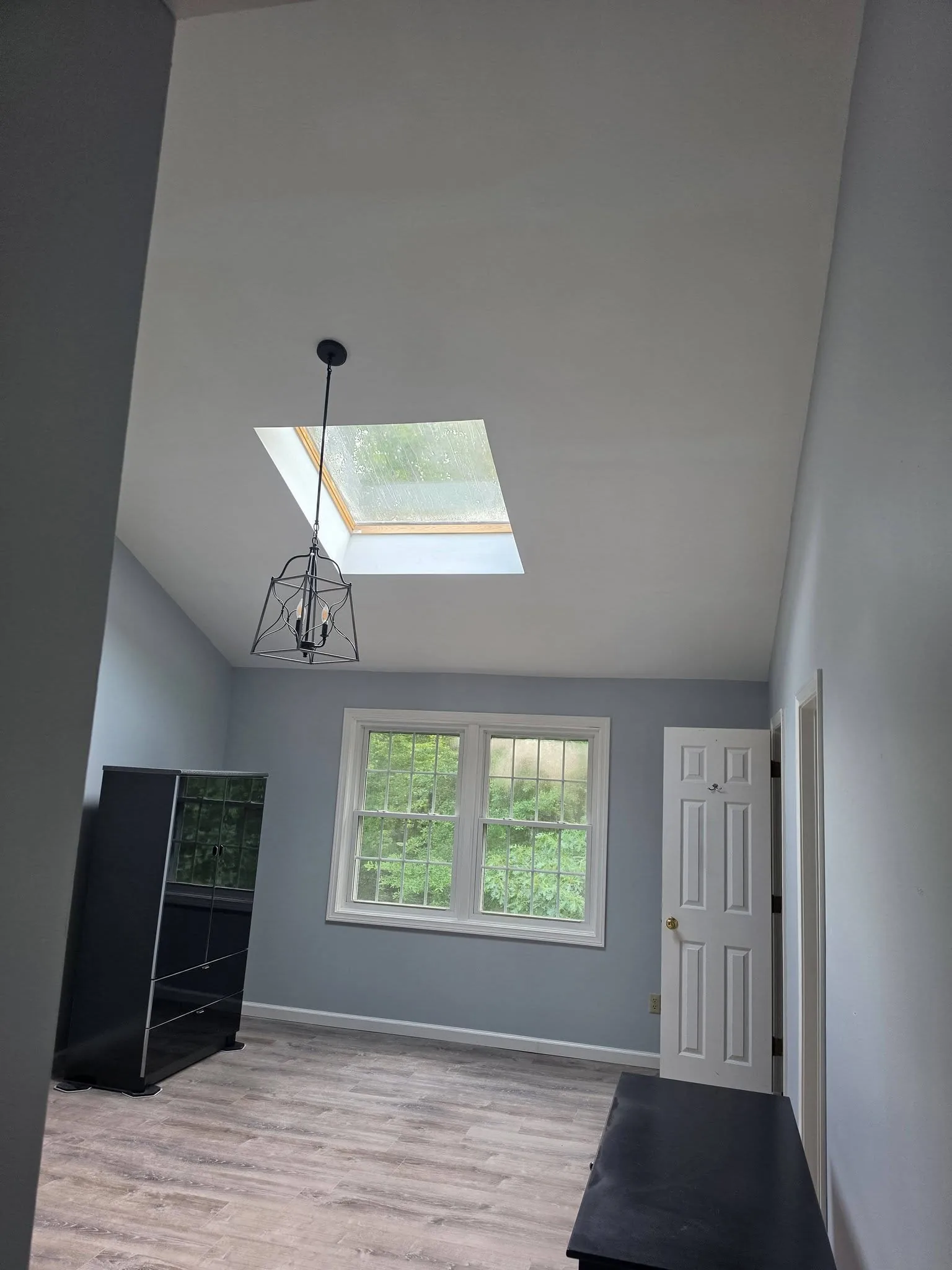 Finished vaulted room with a smooth painted ceiling after popcorn texture removal, new flooring, and fresh paint