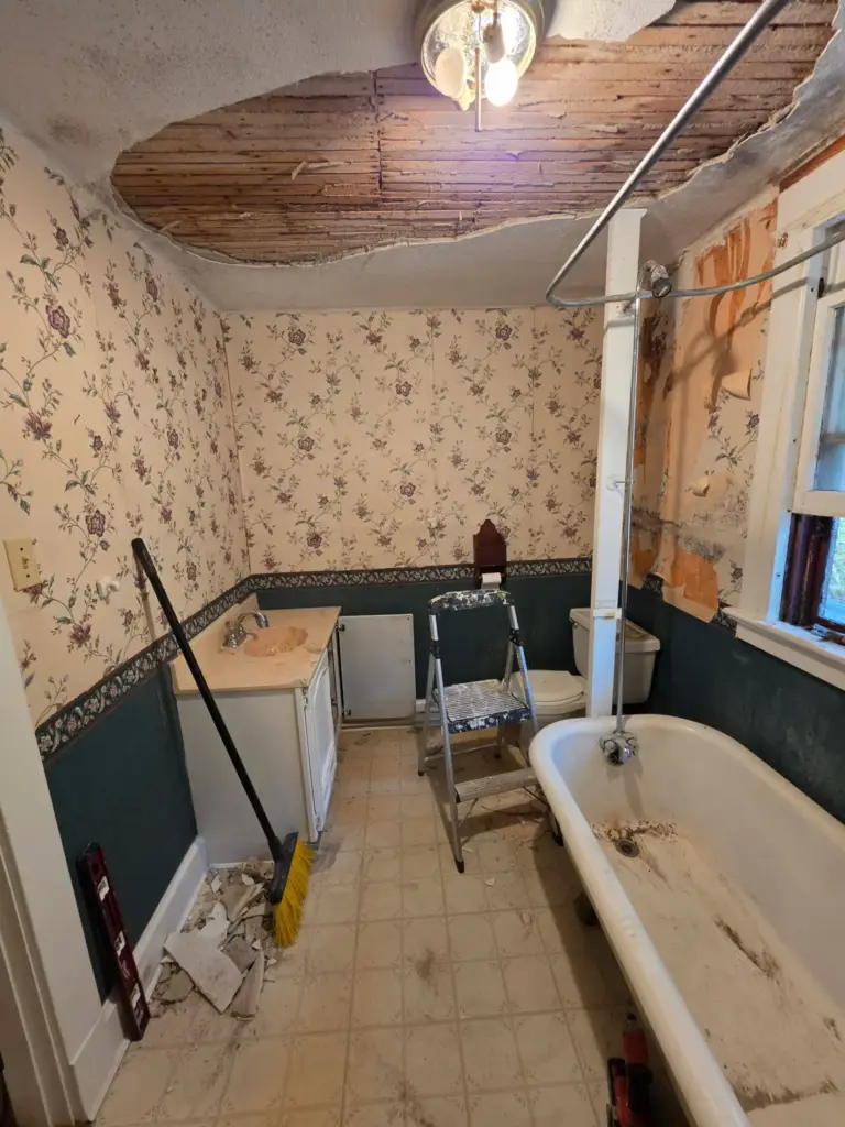 Torrington CT bathroom before remodeling with damaged plaster ceiling, wallpaper, and old vinyl floor